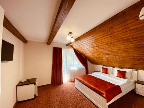 a bedroom with a large bed with a wooden ceiling at PASTRAVARIA ALINA in Sîrbi