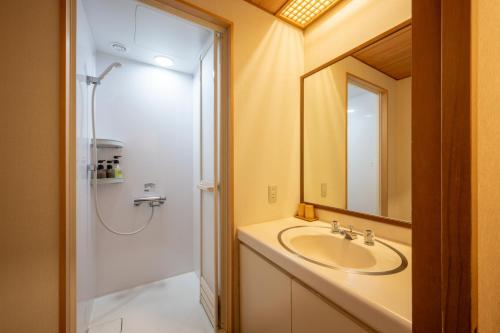 a bathroom with a sink and a shower with a mirror at Yumoto Kissho in Osaki
