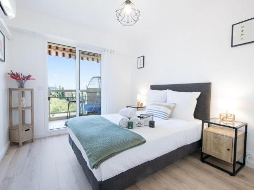 une chambre blanche avec un lit et une grande fenêtre dans l'établissement Appart 4 étoiles, piscine, parking, wifi, à Saint-Raphaël