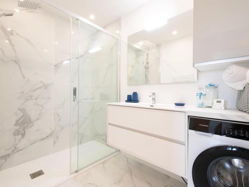 une salle de bain blanche avec une machine à laver et une douche en verre dans l'établissement Appart 4 étoiles, piscine, parking, wifi, à Saint-Raphaël
