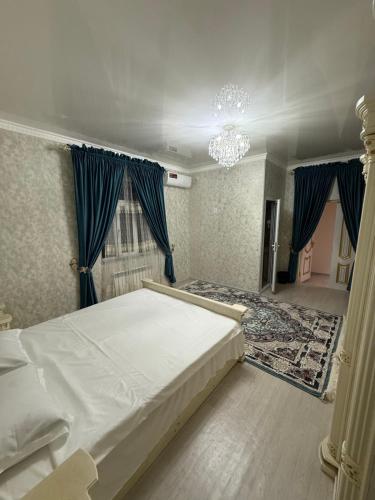 a bedroom with a white bed and blue curtains at Sarzamin Guest House in Khiva
