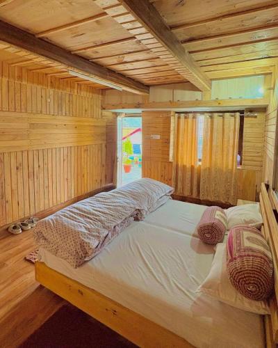 a large bed in a room with wooden walls at Sunlight Homestay Mohana in Chakrāta