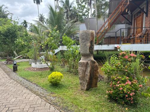 a stone statue in the grass next to a garden at Steps Garden Resort in Negombo