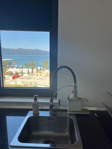 eine Küchenspüle und ein Fenster mit Blick auf den Strand in der Unterkunft Sunset Resort in Vlorë