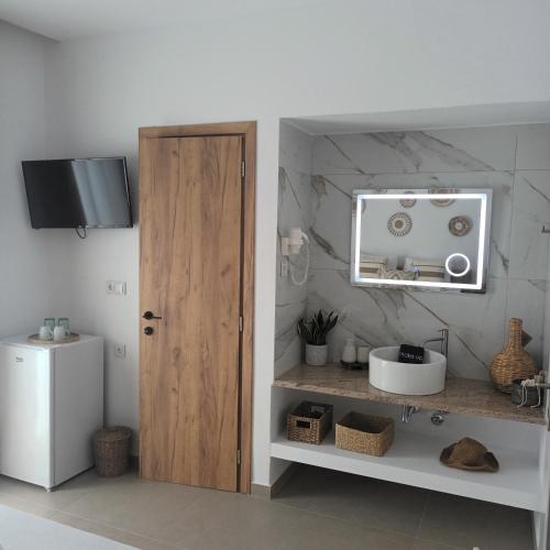 a bathroom with a wooden door and a sink at Maison Kalogiannis in Patitiri