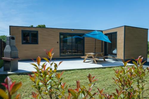 a tiny house with a blue umbrella in the yard at La Tiny L Loches, proche Zoo de Beauval in Loches