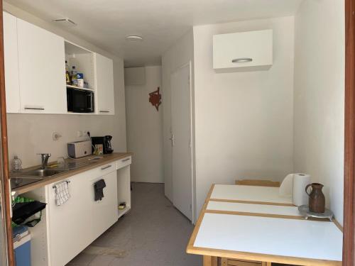 une cuisine avec des armoires blanches et un comptoir dans l'établissement appartement de montagne corsica, à Zicavo