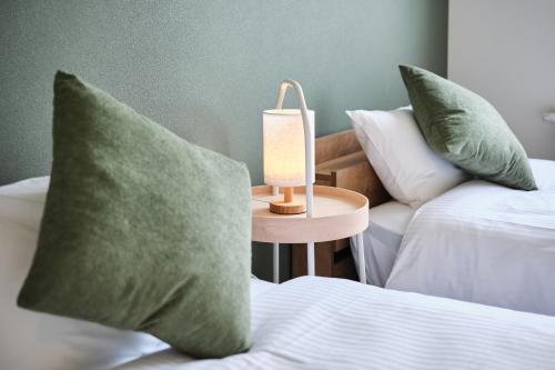 two beds with green pillows and a lamp on a table at Shikauchi Furano in Nakafurano