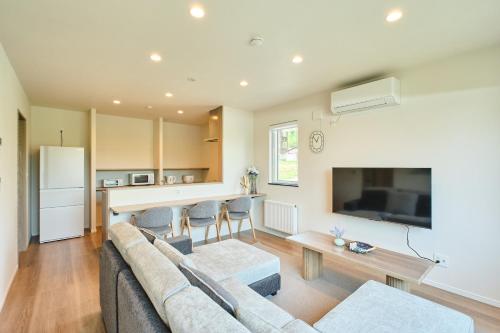 a living room with a couch and a kitchen at Shikauchi Furano in Nakafurano