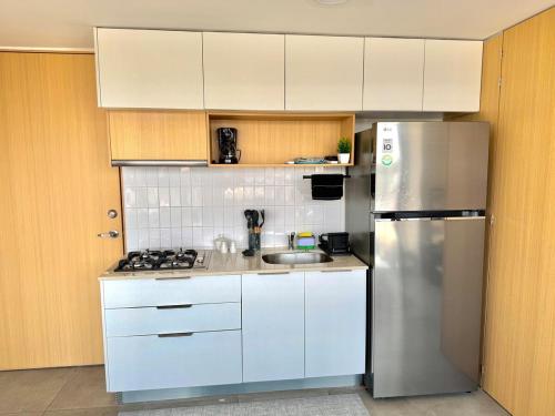 a kitchen with white cabinets and a stainless steel refrigerator at Beautiful apartment near Andares in Guadalajara