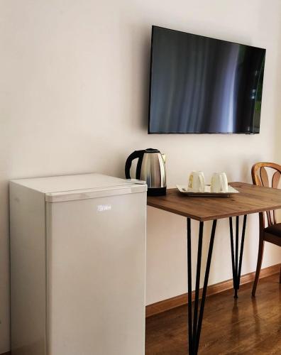 a small refrigerator next to a table with a tv at Lomtadze Family Wine Hotel in Ambrolauri