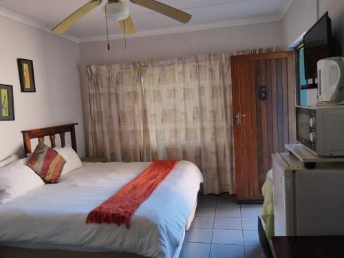 a bedroom with a bed and a tv and a window at La Rochelle Inn in Richards Bay