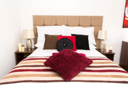 a bedroom with a large bed with red pillows at Trivelles Mayfair,stockport in Manchester