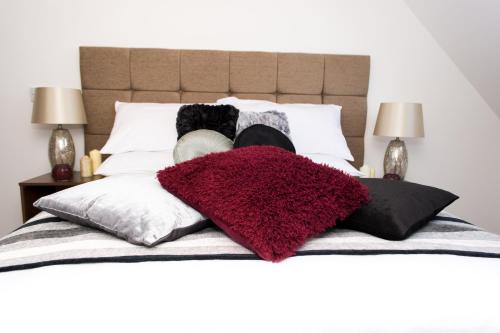 a bed with a red blanket and pillows on it at Trivelles Mayfair,stockport in Manchester