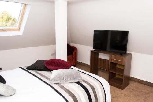 a bedroom with a bed and a flat screen tv at Trivelles Mayfair,stockport in Manchester
