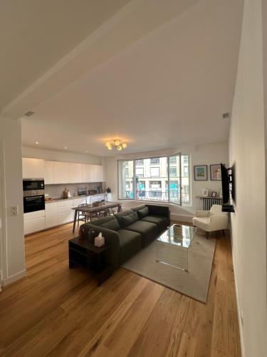 un salon avec un canapé noir et une cuisine dans l'établissement Appartement Trocadéro, à Paris