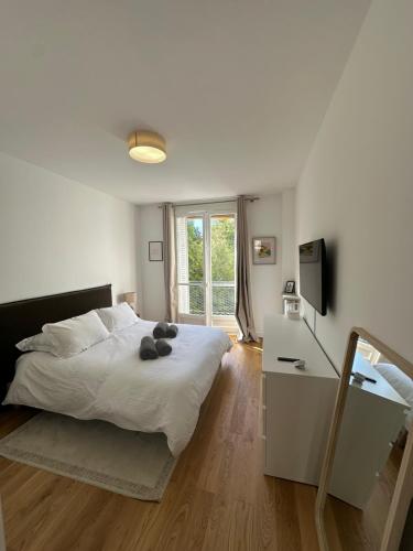 une chambre avec un grand lit blanc et une fenêtre dans l'établissement Appartement Trocadéro, à Paris