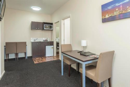 a room with a table and chairs and a kitchen at 540 on Great South Motel in Auckland