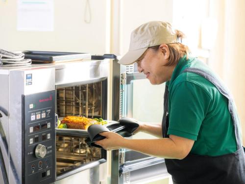 a man is putting food into an oven at Tokai City Hotel - Vacation STAY 83890v in Tokai