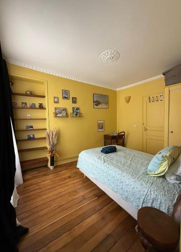 une chambre avec un lit, des murs jaunes et du parquet dans l'établissement Bergère Opéra Trévise - 2 connecting rooms with private bathroom and 1 study room - 35 m2, à Paris
