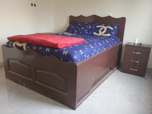 een bed met een houten frame en een rode deken erop bij Sky Blue VIP Guest House Buea in Buea