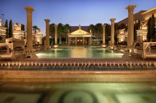 a large pool with chairs and a building at Caesars Palace Hotel & Casino in Las Vegas