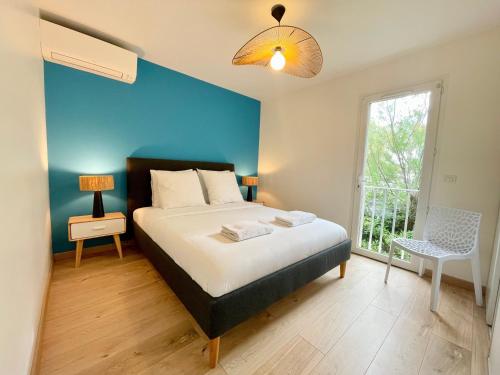 Cet appartement comprend une chambre dotée d'un lit avec un mur bleu et une fenêtre. dans l'établissement PGH N44 - Grand Duplex Vue Mer, 50 m de la plage, à La Grande Motte