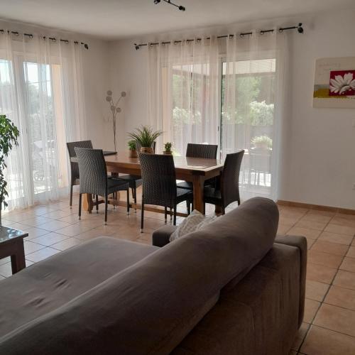 un salon avec un canapé, une table et des chaises dans l'établissement Charmante villa tout confort,sans vis a vis avec piscine, à Maraussan