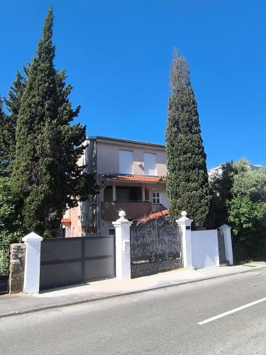 a house with a black and white fence and two trees at Old House - Ferienhaus in Selce