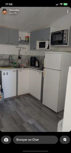 une cuisine avec des armoires blanches et un réfrigérateur blanc dans l'établissement Camping Les Amandiers 4 étoiles, à Gallargues-le-Montueux