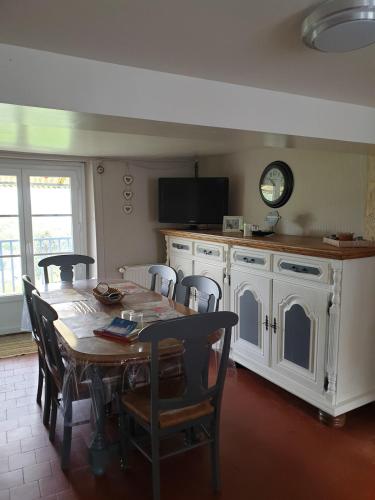 une cuisine avec une table, des chaises et une horloge dans l'établissement Maison de campagne, à Corancy