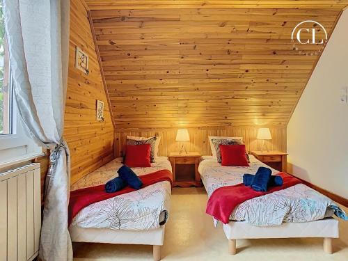 two beds in a room with wooden walls at Au murmure de l eau in Ebersheim