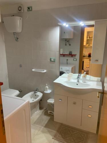 a white bathroom with a sink and a toilet at La Pigna in Marina di Sorso