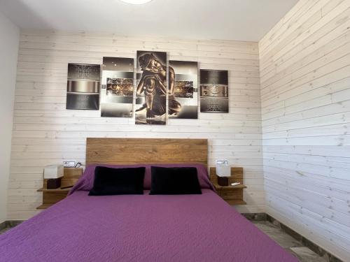 a bedroom with a purple bed with four pictures on the wall at River Dreams in Deltebre