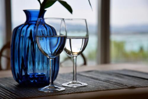 two wine glasses and a vase on a table at 青の家 in Kouri-shima