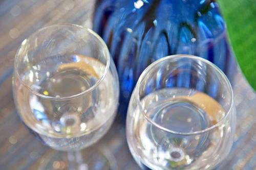 two empty wine glasses sitting next to a blue vase at 青の家 in Kouri-shima