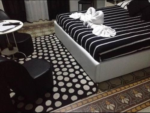 a bed with black and white sheets and a table and chairs at Alba Camere in Palermo