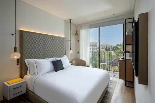 une chambre avec un grand lit blanc et un balcon dans l'établissement Hotel Nucha-Fattal Colors, à Jérusalem