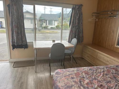 a bedroom with a table and chairs and a window at Road Runner Motel in Merritt