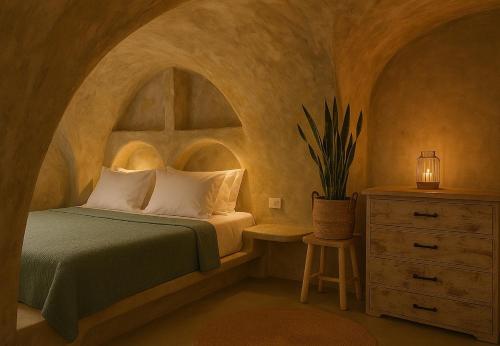 a bedroom with a bed and a dresser with a lamp at Selora Cave in Pyrgos