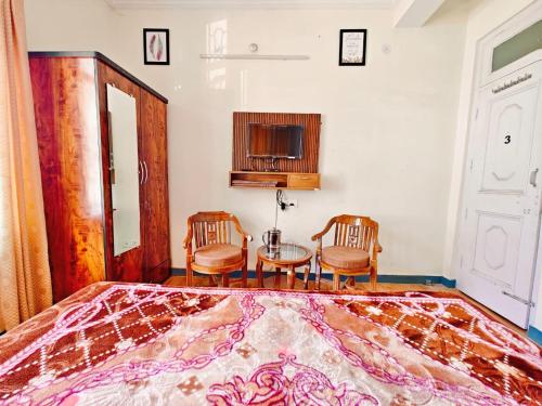 a bedroom with a bed and two chairs and a table at Frosty Woods Homestay in Shimla