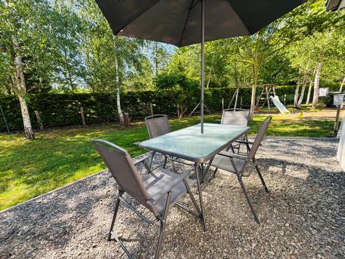 a table and chairs with an umbrella and a playground at Gîte à la campagne 2 in Cérans-Foulletourte