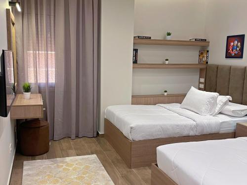 a hotel room with two beds and a television at شقة فاخرة 3 غرف نوم و حديقة خاصة في الشيخ زايد - Zayed Suites A in Sheikh Zayed