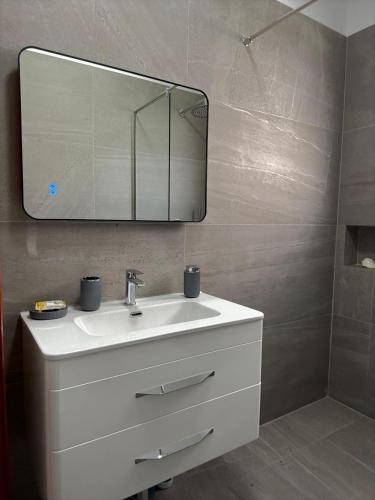 a bathroom with a white sink and a mirror at GuestHouse Brahja, Tirana in Sauk