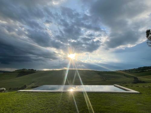 a sun shining through the sky over a field at Agriturismo Il Casalino in Pienza