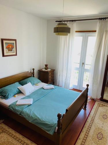 a bedroom with a bed with blue sheets and a window at Vila Zorka in Trebinje