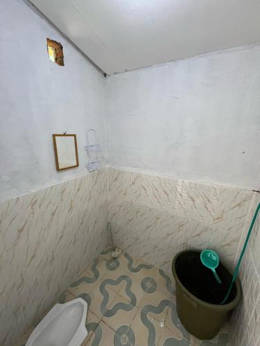 a bathroom with a toilet and a trash can at Ikua Tanjuang in Situjuhbatul