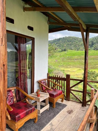 a porch of a house with two chairs and a table at Ikua Tanjuang in Situjuhbatul