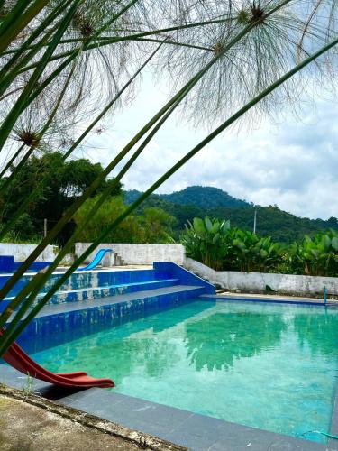 a blue swimming pool with a red slide in the middle at Ikua Tanjuang in Situjuhbatul