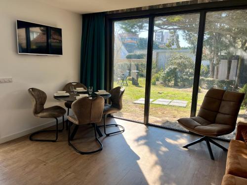 a dining room with a table and chairs and a large window at BeachHouse AAN ZEE in Noordwijk aan Zee